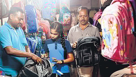 With schools set to reopen on Thursday, a student buys a bag with her father in Karimnagar.