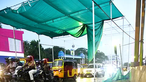 The green cloth erected to cover the vehiculars to beat the heat in hot days, poses dangerous threat after it falls off the fittings following heavy wind, at Pachiappan college signal in Chennai on Tuesday evening.