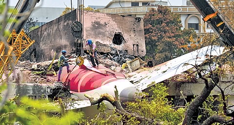 FILE | A crane removing aeroplane's tail from the wreckage after the June 12 Air India flight 171 crash, is pictured in a residential area near the airport in Ahmedabad on June 14, 2025