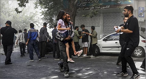 A man carries a wounded girl after an explosion in downtown Tehran amid Israel's three-day campaign of strikes against Iran, Sunday, June 15, 2025.