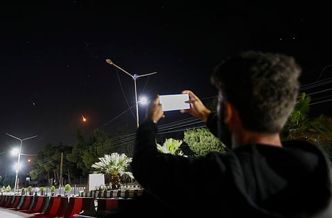 A Syrian man takes pictures with his mobile phone of Iranian missiles on their way toward Israel, as they pass over Damascus airspace, Syria, Friday, June 13, 2025.
