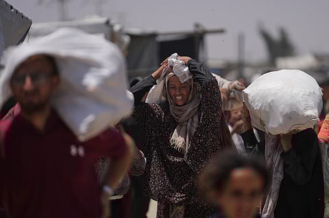 Palestinians carry bags containing food and humanitarian aid packages delivered by the Gaza Humanitarian Foundation, a U.S.-backed organization, in Rafah, southern Gaza Strip, Monday, June 16, 2025.