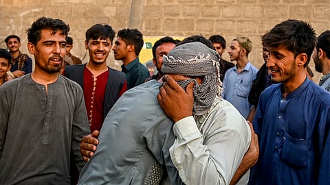 Afghan refugees embrace each other before leaving for Afghanistan at a bus stand in Karachi on April 8, 2025.