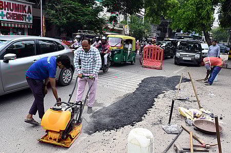 PWD workers fix a pothole on a road during the 24-hour pothole repair drive, at CR Park, in New Delhi,
