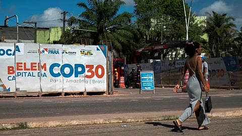 A woman walks past an infrastructure project underway for COP30 in Belem, Para state, Brazil, on June 16, 2025. Brazil will host the UN climate conference COP30 in November in the Amazonian city of Belem.
