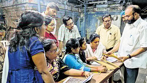 Mani Maran showing palm leaf manuscripts to students.