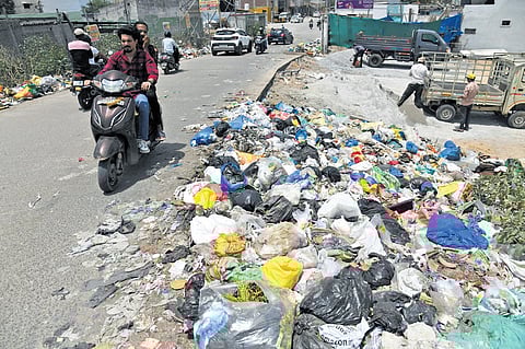 Bikers grimace as they pass a heap of garbage emitting foul smell just a few metres from Sunnam Cheruvu.