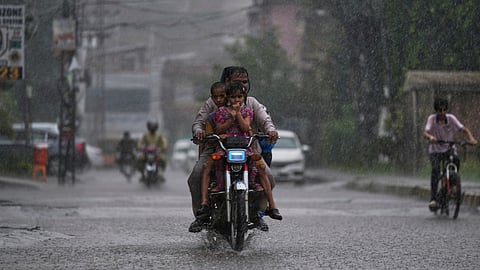 A motorcyclist with his family drive on a street during heavy rainfall, in Rawalpindi, Pakistan, Friday, June 27, 2025.