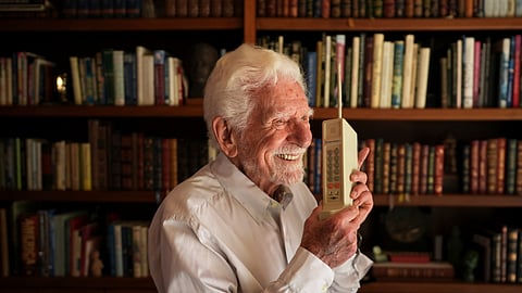 Martin Cooper, who led the team that built the first mobile cellphone, sits behind a prototype of that phone at his home, April 4, 2025, in San Diego