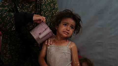 Rida Abu Hadayed, 32, cools off her 2-year-old daughter Azhar with water in their tent at a camp for displaced people in Khan Younis, southern Gaza Strip, Tuesday, July 1, 2025. 