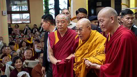 Tibetan spiritual leader the Dalai Lama, in yellow robe, is helped by attendant monks as he arrives to preside over an event during which Tibetan exiles prayed for his longevity, a day before his 90th birthday, in Dharamshala, India, Saturday, July 5, 2025.