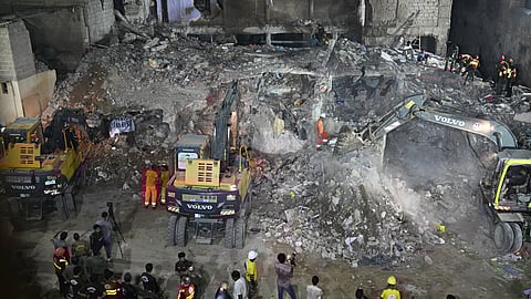 Rescue workers search for victims amidst the debris of a collapsed residential building in Karachi on July 4, 2025. A five-storey building collapsed in Pakistan on July 4, killing at least seven people and injuring eight, officials said, with rescuers searching through the rubble for trapped victims. 