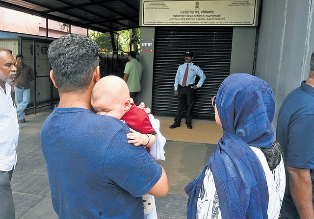  A family from Malappuram, carrying an infant, waiting outside the Kozhikode Passport Office after it was forcibly closed by protesters 