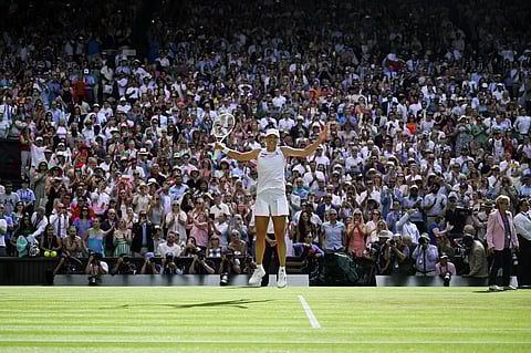 Italy's Jannik Sinner celebrates with the winner's trophy following his victory against Spain's Carlos Alcaraz at the end of their men's singles final tennis match on the fourteenth day of the 2025 Wimbledon Championships at The All England Lawn Tennis and Croquet Club in Wimbledon, southwest London, on July 13, 2025.