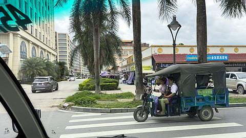 This photo taken on May 26, 2025 shows workers driving a three-wheeler along a street inside the Golden Triangle Special Economic Zone along the Mekong river in the Bokeo province of Laos. 