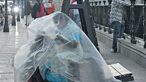 A woman and a child use a plastic sheet to shield themselves from rain at 
the Tank Bund in Hyderabad on Thursday