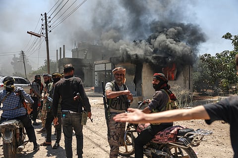 Bedouin fighters gather in front a burned shop at Mazraa village on the outskirts of Sweida city, during clashes between the Bedouin clans and Druze militias, southern Syria, Friday, July 18, 2025.