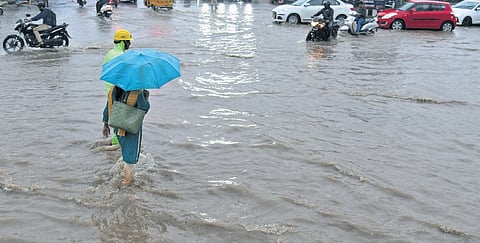 A woman wades through a waterlogged road in Madhapur