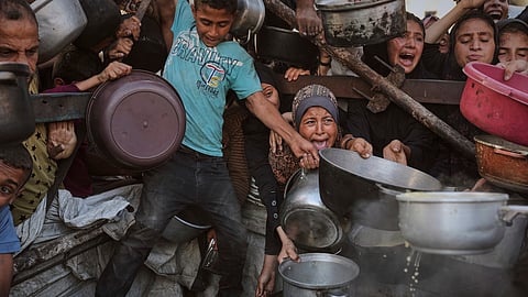 Palestinians struggle to get donated food at a community kitchen in Gaza City, northern Gaza Strip.