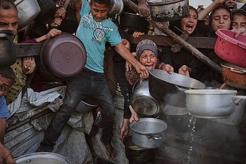 Palestinian children wait for food at a distribution point in Nuseirat, in the central Gaza Strip, on June 11, 2025.