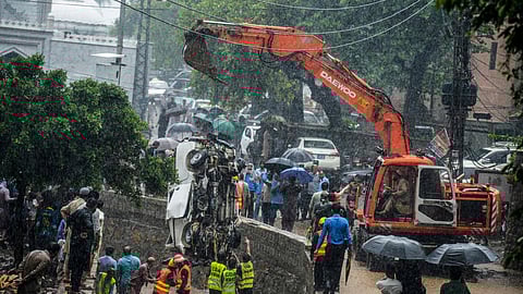 Rescuers and people look as a crane removes the wreckage of a van from a drainage after heavy monsoon rains in Islamabad on July 21, 2025