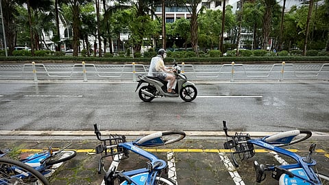 A motorcyclist drives past fallen bicycles in the rain caused by tropical storm Wipha in Hanoi, Vietnam, on Tuesday, July 22, 2025. 