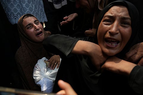 Palestinians struggle to get donated food at a community kitchen, in Gaza City, northern Gaza Strip, Saturday, July 26, 2025.