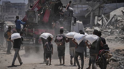 Palestinians carry sacks of flour unloaded from a humanitarian aid convoy that reached Gaza City from the northern Gaza Strip (Photo | AP)