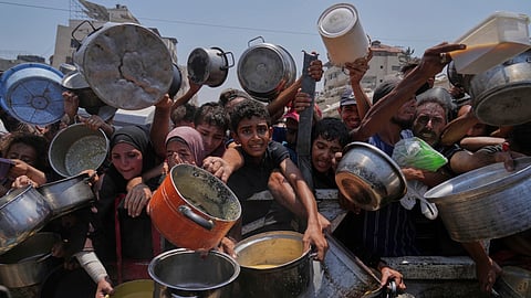 Palestinians struggle to get donated food at a community kitchen, in Gaza City, northern Gaza Strip, Saturday, July 26, 2025.