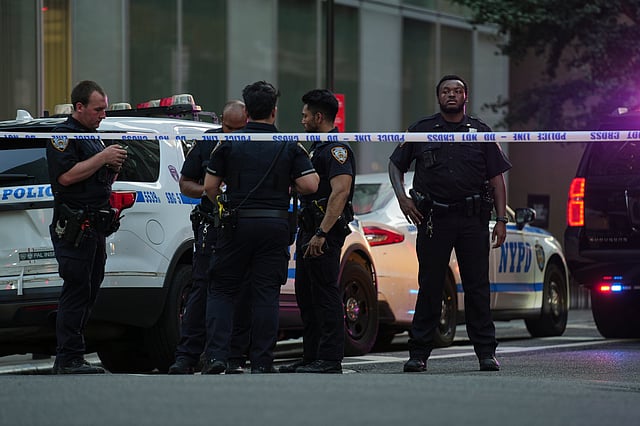 A New York Police officers gather at the scene on 52nd Street outside a Manhattan office building where two people were shot, including a New York police officer, Monday, July 28, 2025, in New York.