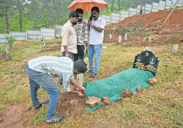 Relatives cleaning the grave of the landslide victims ahead 
of the anniversary | E Gokul