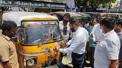District Collector P Akash sticking the promo sticker on an auto rickshaw at the auto stand near the Perarignar Anna Bus Stand in Velippalayam in Nagapattinam to promote the upcoming fourth book fair in the district to the public.