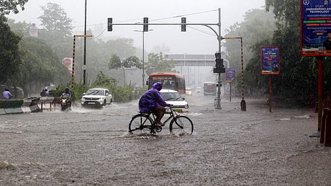 Commuters wade through a waterlogged road amid heavy rain, in New Delhi on Tuesday.