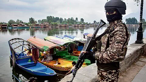 A soldier holding a gun standing near the picturesque Dal Lake in Srinagar
