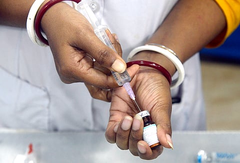 A health worker fills a syringe with measles and rubella (MR) vaccine.