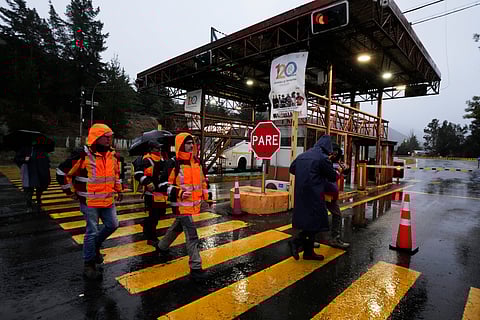 Workers walk at the entrance of El Teniente copper mine, operated by Codelco in Chile, where a collapse killed one worker and trapped five others underground, leading to a suspension of operations in Rancagua Chile, Friday, Aug. 1, 2025.