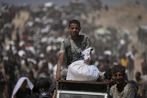 Palestinians carry sacks of flour taken from a humanitarian aid convoy en route to Gaza City, in the outskirts of Beit Lahiya, northern Gaza Strip, Friday, Aug. 1, 2025. 