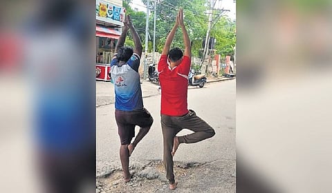 The viral photo showing two barefoot men striking yoga poses inside a pothole in Hyderabad.