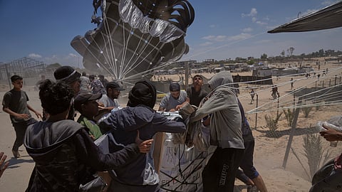 Palestinians rush to collect humanitarian aid airdropped by parachutes into Deir al-Balah, central Gaza Strip, Tuesday, Aug. 5, 2025. 