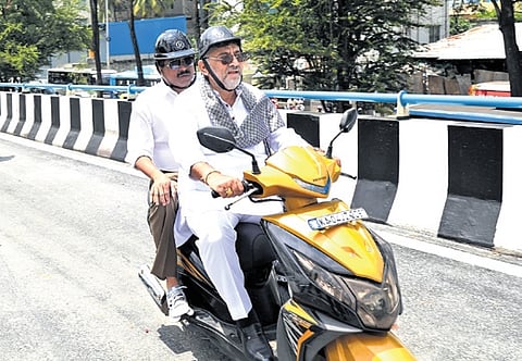 DCM DK Shivakumar rides a two-wheeler with Urban Development Minister Byrathi Suresh after inspecting Hebbal flyover work on Tuesday