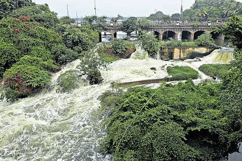 Water gushes out from the Hussainsagar as the lake reaches its Full Tank Level (FTL); a man clears water logged in front of a house in Patny Colony on Friday.