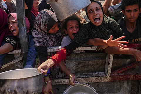 Palestinians struggle to receive aid at a community kitchen in Gaza City, northern Gaza Strip, Monday, Aug. 4, 2025.