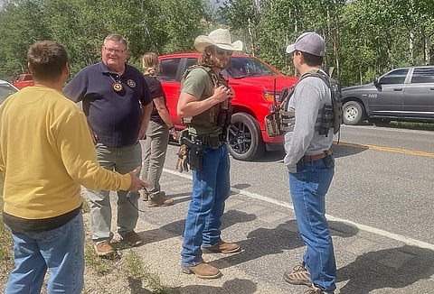 Law enforcement officers stand at the scene where Michael Brown, a suspect in a shooting at a Montana bar that left four people dead, was apprehended on Friday, Aug. 8, 2025, outside of Anaconda, Mont. 