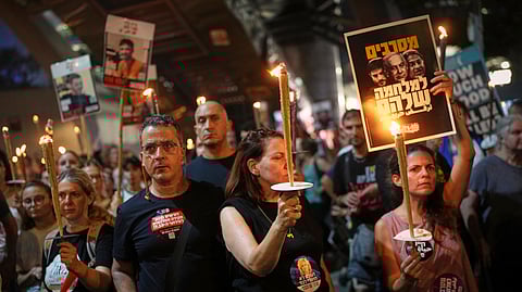 Demonstrators light torches during a protest demanding the release of all hostages held by Hamas in the Gaza Strip and calling for an end to the war in Tel Aviv, Israel, Saturday, Aug. 9, 2025.