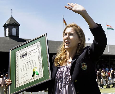 International Tennis Hall of Fame inductee Monica Seles waves to the crowd as she holds her plaque during ceremonies in Newport, R.I., July 11, 2009