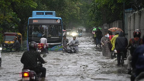 Commuters wade through a waterlogged road amid heavy rainfall, in New Delhi, Thursday, Aug. 14, 2025. 