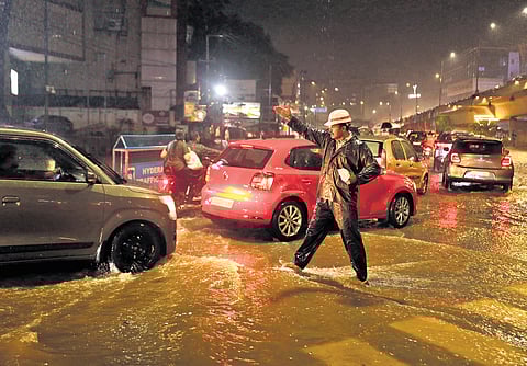 A traffic cop regulates traffic on a waterlogged road in Hyderabad during the recent rains.