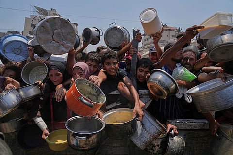 Palestinians struggle to get donated food at a community kitchen in Gaza City, northern Gaza Strip, July 26, 2025.