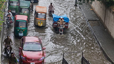 Vehicles and motorcyclists drive through a flooded road after heavy rainfall in Peshawar, Pakistan, Monday, Aug. 18, 2025.