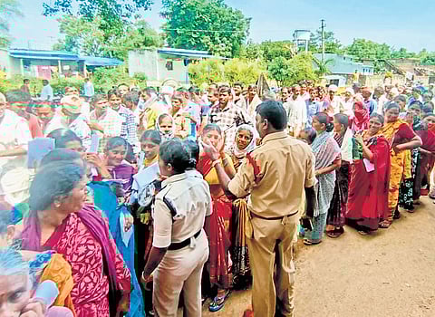 Police personnel maintain order as hundreds of farmers stand in queues in Kuravi mandal of Mahbubabad district on Thursday